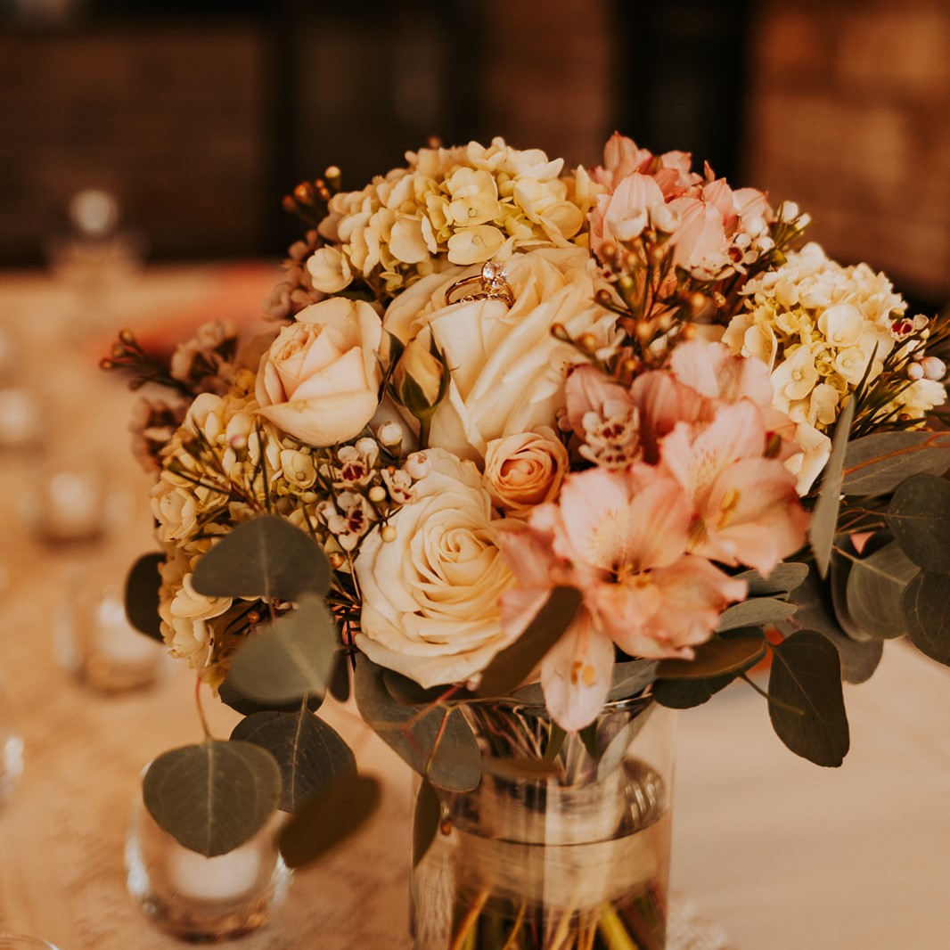 Roses arranged in a vase with wedding ring on top