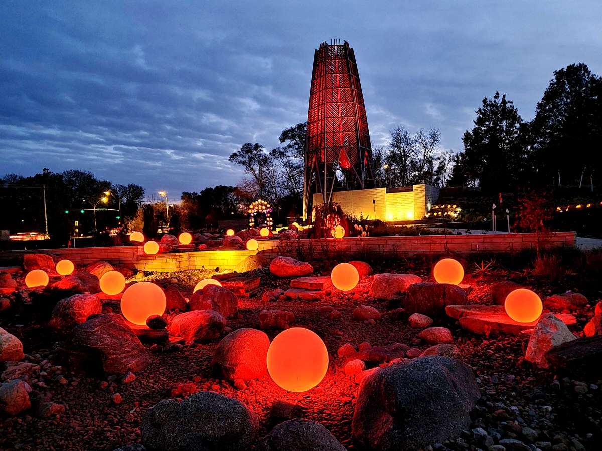 Lighted orange orbs and tower in a garden