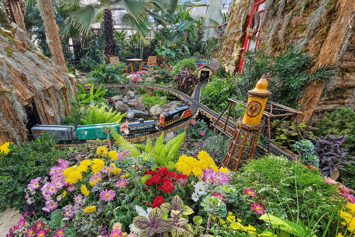 Garden scale train amongst flowers and a tiny water tower