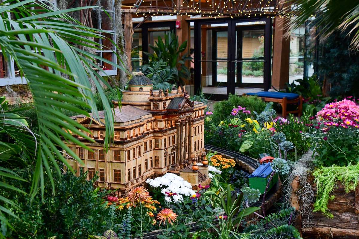 Miniature building surrounded by flowers in a garden railroad display