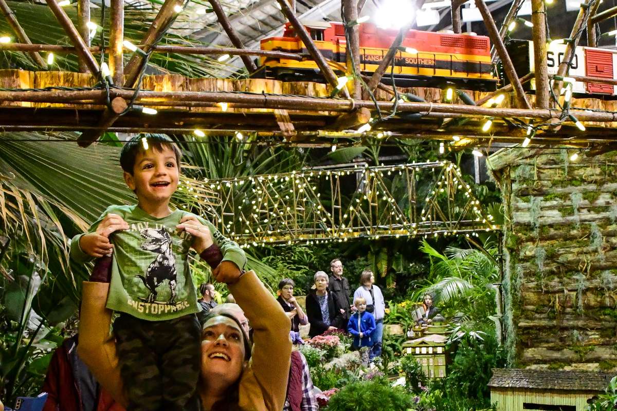 Child watching a garden scale train on a bridge