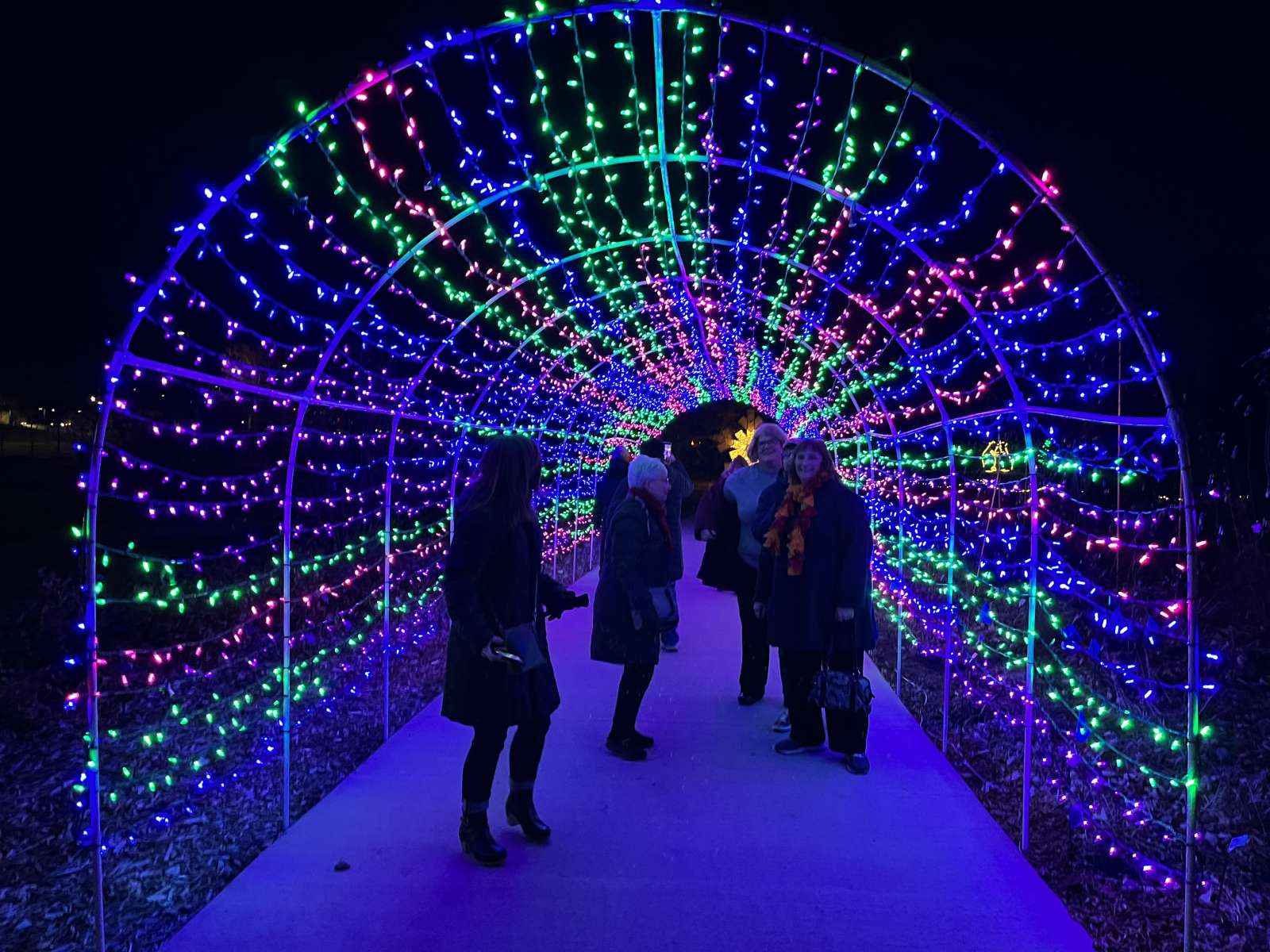 cascading tunnel of twinkling lights with people walking through