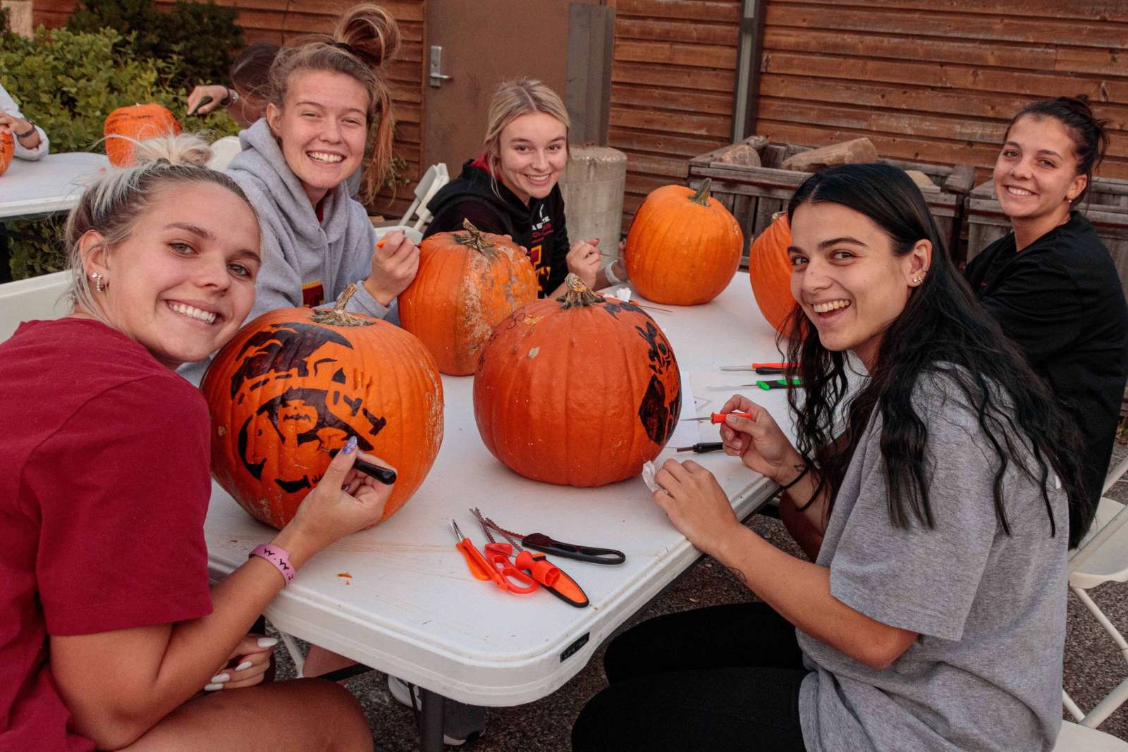 Young women carve pumpkins